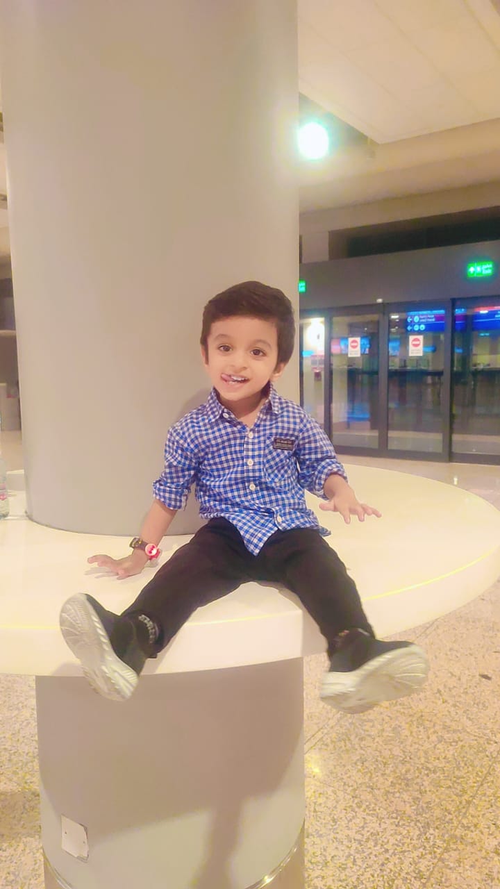 Ibrahim sitting and smiling in a blue checked shirt